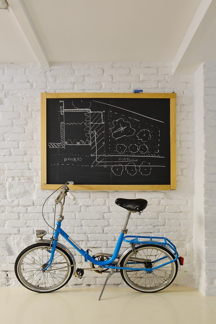 Blaues Klapprad vor einer Tafel mit Architektur-Zeichnung