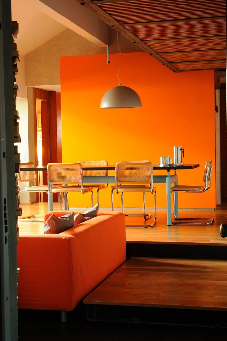 Dining table in front of orange wall on raised platform
