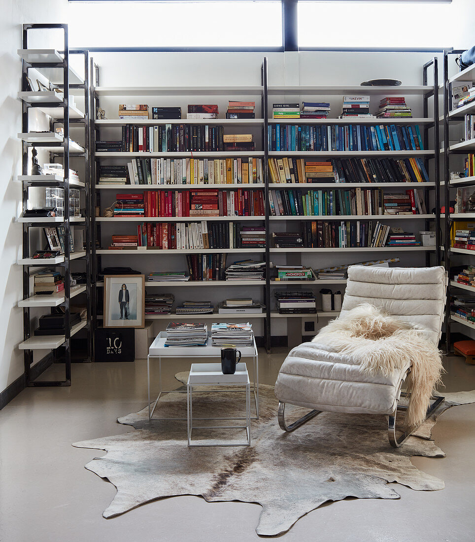 Custom bookshelves, classic recliner and side table on cowhide rug in loft apartment