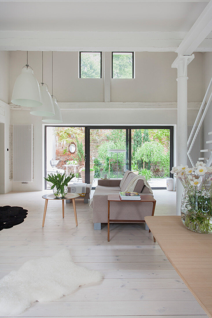 Helles Wohnzimmer mit doppelter Raumhöhe und weißem Boden
