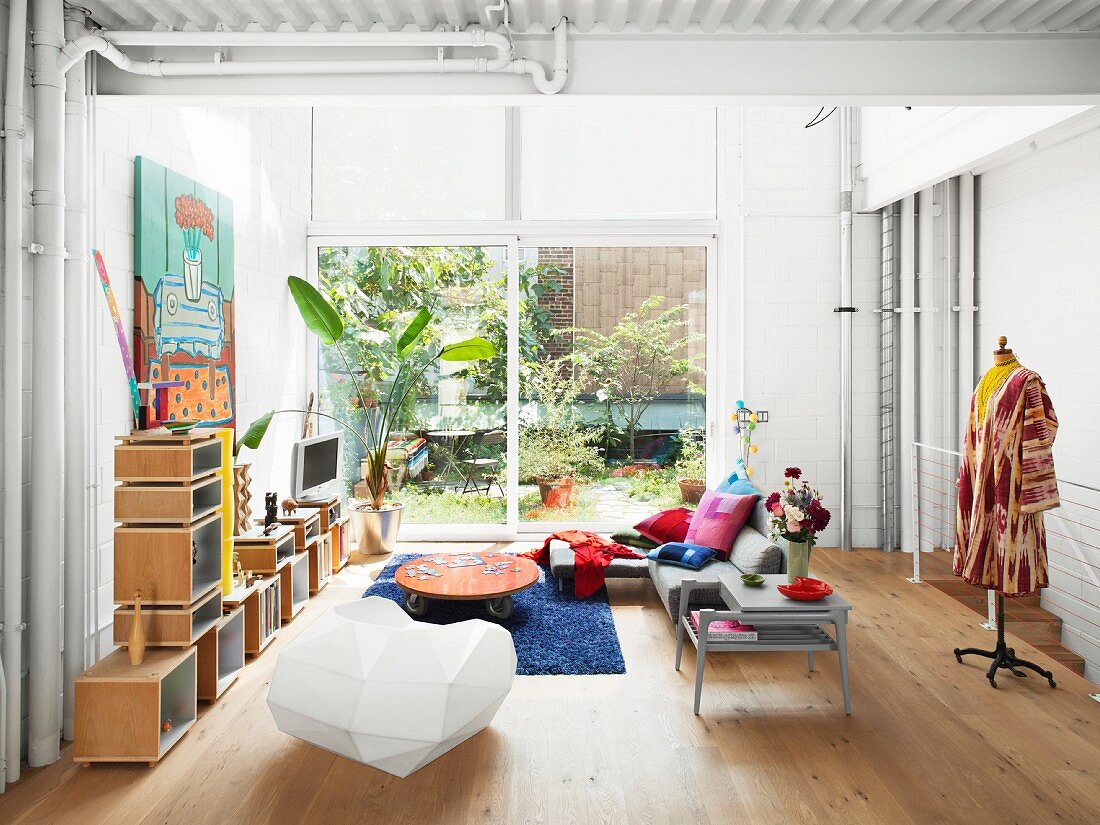 Regalmodulen, Designerstuhl und Kleiderpuppe in hohem Wohnzimmer mit Terrassentür