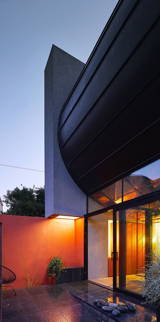 Architect-designed house with glass wall at dusk