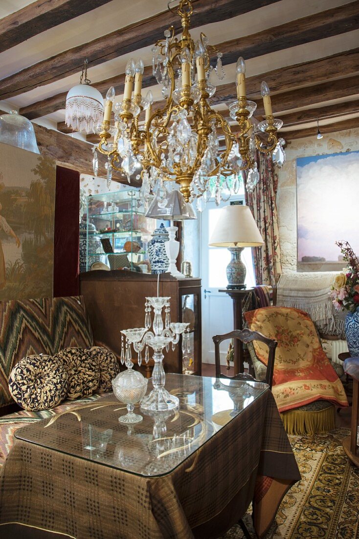 Chandelier above table with glass top over tablecloth