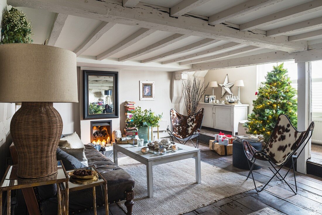 Weihnachtlicher, rustikaler Wohnbereich mit Kaminofen, Kerzenlichtern und Weihnachtsbaum