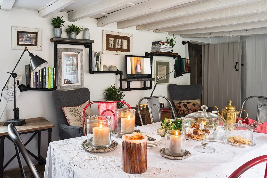 Schwarzes Regal aus Rohren und Holzbrettern in Cottage mit weihnachtlich gedecktem Esstisch