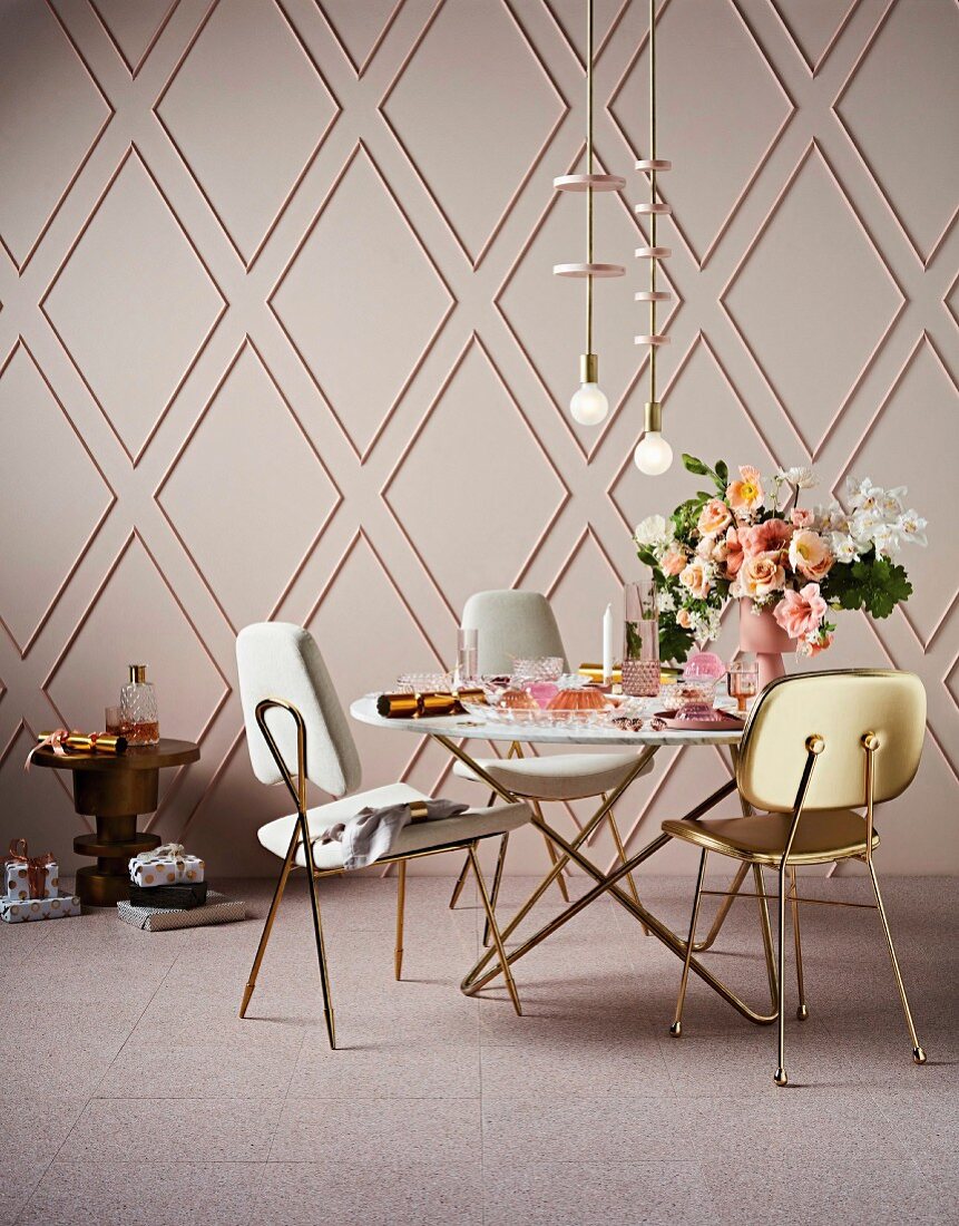 Dining table and chairs with gold legs against rhombus wall