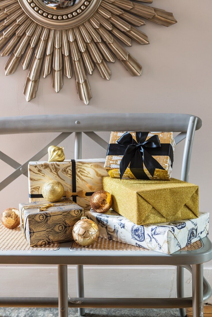 Presents glamorously wrapped in gold and blue on wooden bench