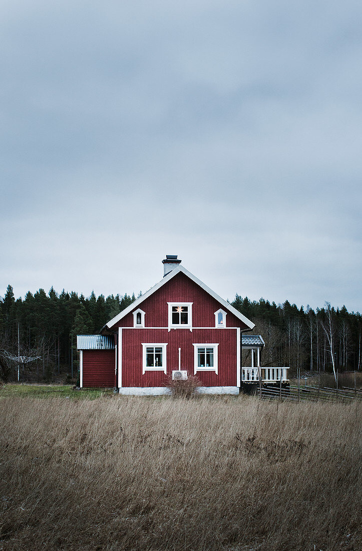 Red, lonely Swedish house under grey cloudy sky