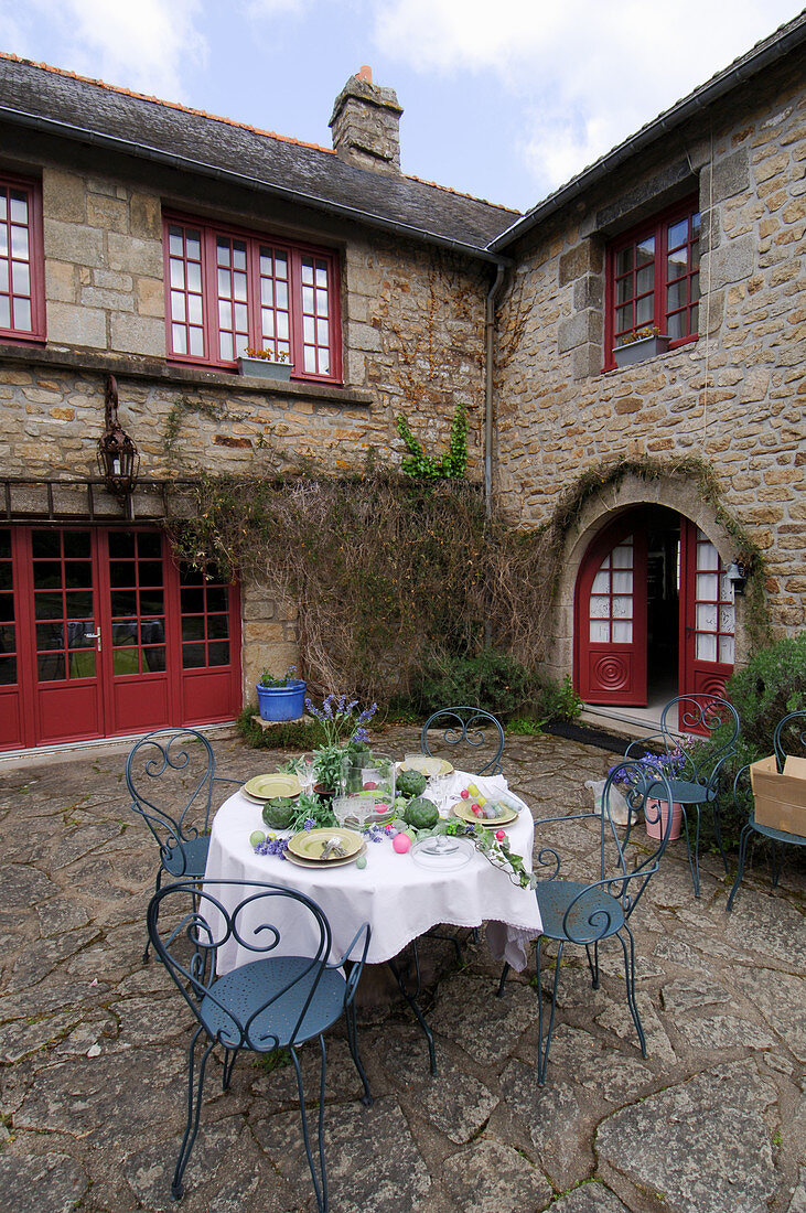 Gedeckter Gartentisch im Innenhof eines französichen Bauernhofes