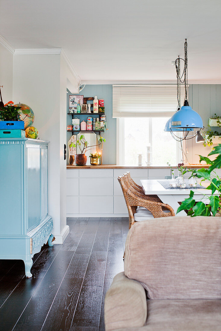 Blick auf weiße Küche und hellblau lackierte Kommode mit Türen in offenem Wohnraum