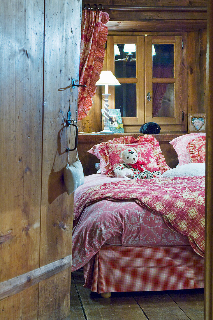 View into rustic bedroom with textiles in shades of red and pink