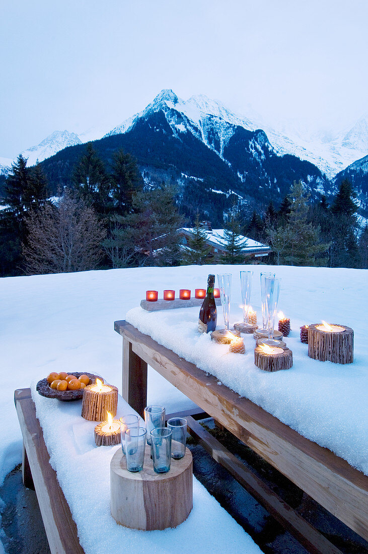 Romantisch gedeckter Holztisch und Bank im Schnee
