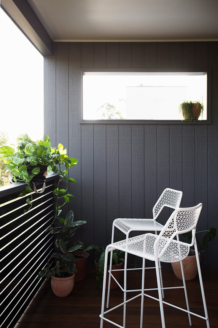 weiße Barhocker aus Metall auf Balkon mit Pflanzen