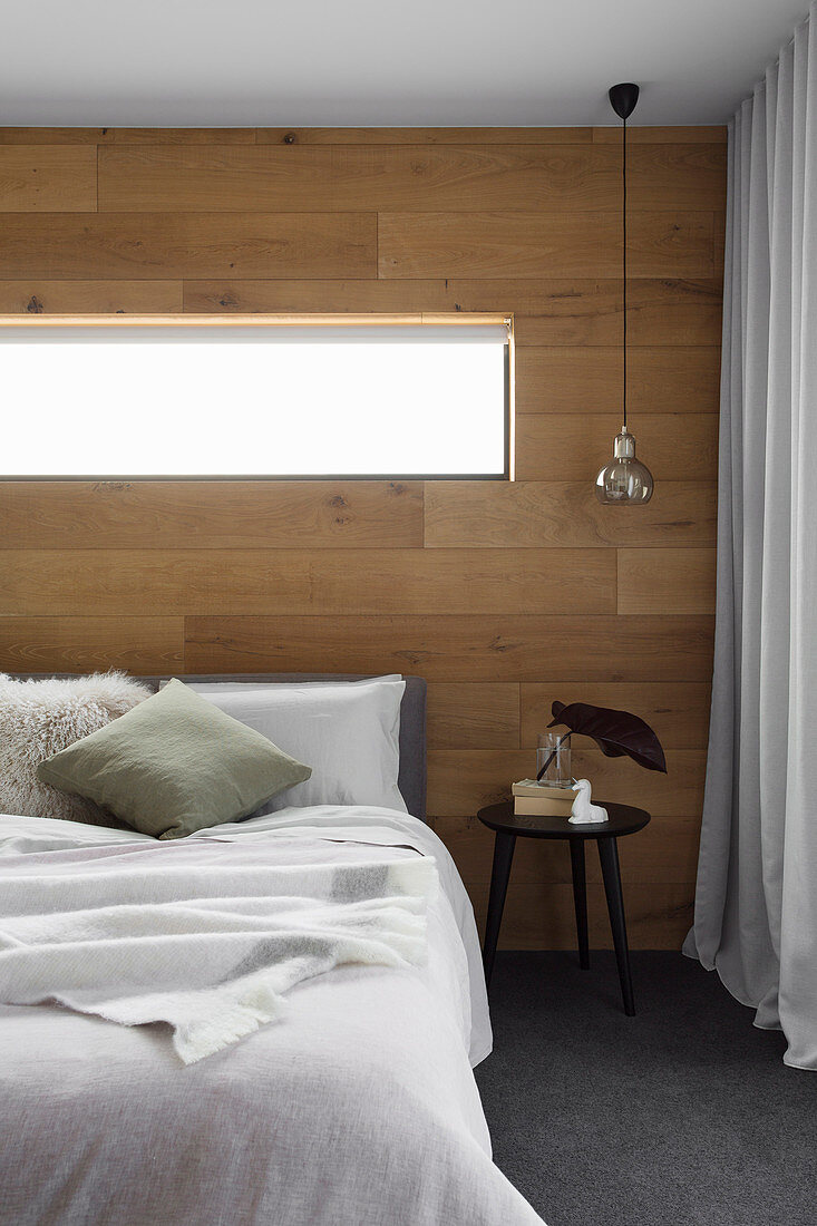 Doppelbett im Schlafzimmer mit Wand aus recyceltem Eichenholz