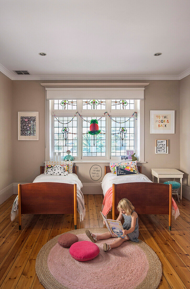 Kinderschlafzimmer mit zwei Einzelbetten und Buntglasfenstern
