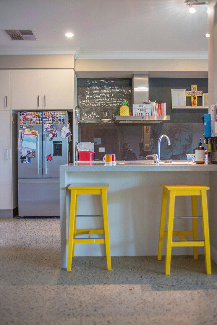 Modern kitchen with yellow stools and blackboard on the wall
