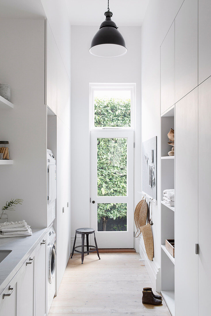 Waschküche ganz in Weiß mit Einbauschräken und Gartentür