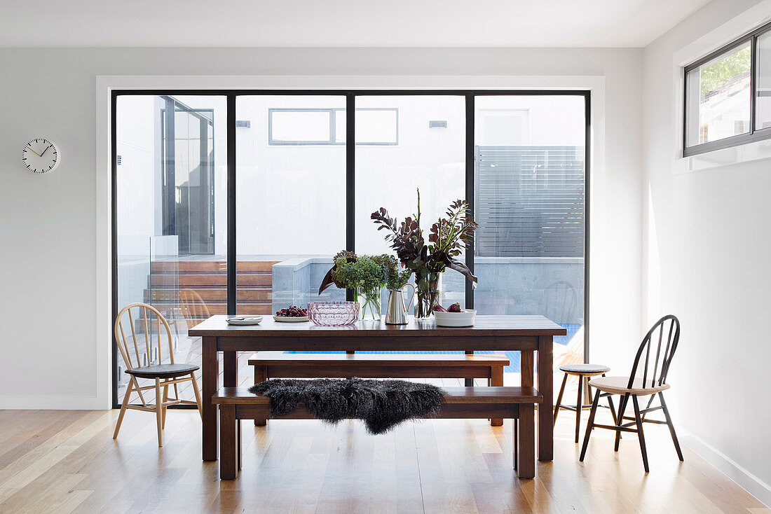 Esstisch mit Bänken und Stühlen vor Terrassentür in offenem Wohnraum