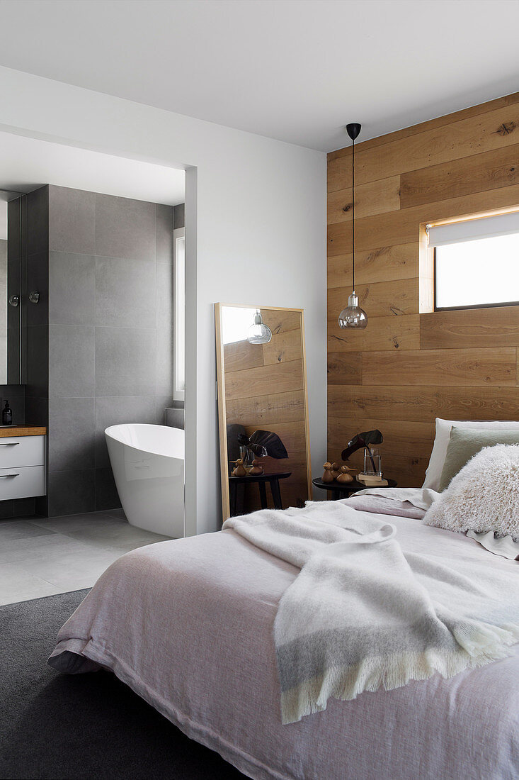 Doppelbett im Schlafzimmer mit Wand aus recyceltem Eichenholz, Blick in Bad Ensuite