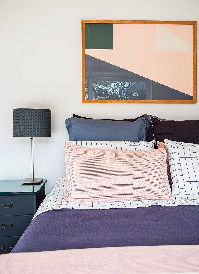Doppelbett mit Kissen, Nachttisch mit Lampe und modernes Bild im Schlafzimmer