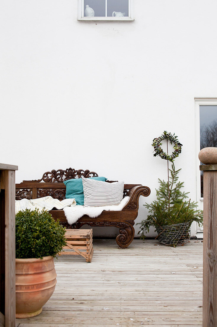 Verschnörkelte Holzbank an der Hauswand auf der Terrasse