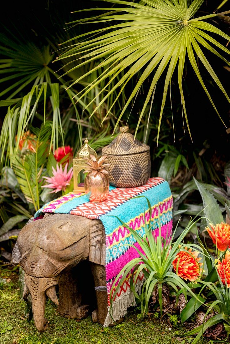 Bunter Teppich und Deko auf einem Holzelefanten im exotischen Garten