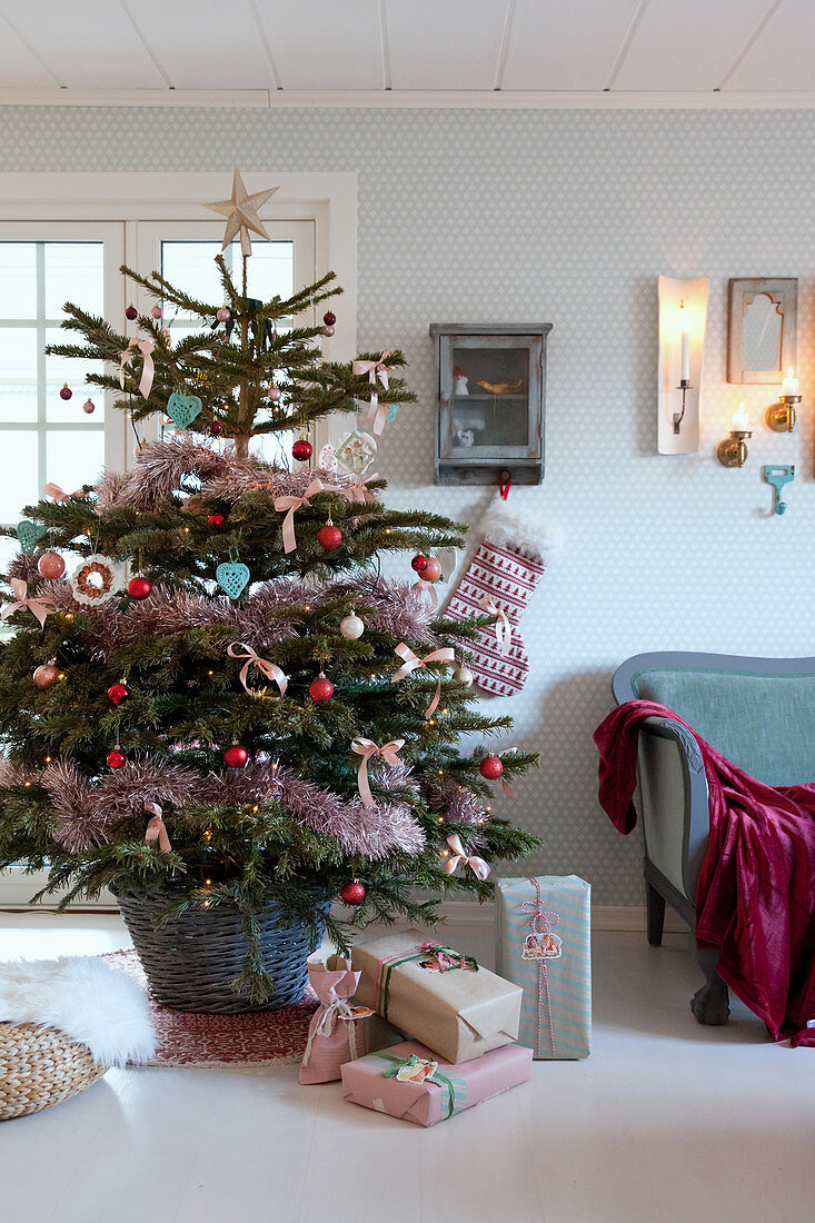 Geschmückter Weihnachtsbaum im Korb mit verpackten Geschenken