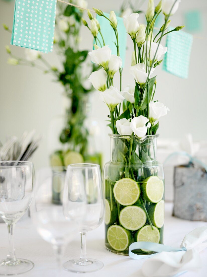 weiße Rosen im Glaskrug mit Limettenscheiben als Tischdeko