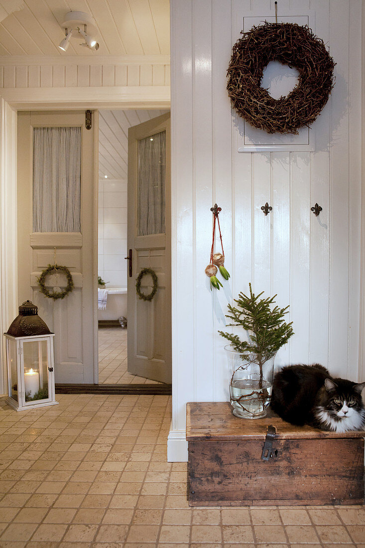 Katze auf einer Holztruhe im Flur im Landhausstil mit Doppeltür und Winter-Deko