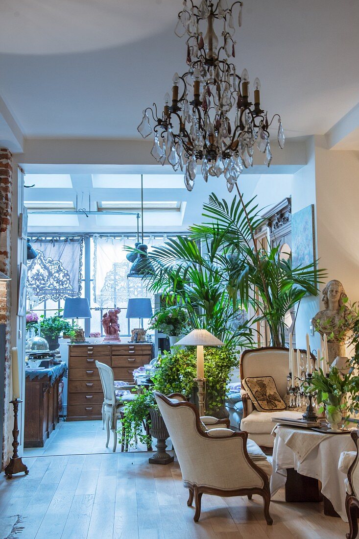 Eleganter Salon mit Grünpflanzen, Kronleuchter und antikem Flair