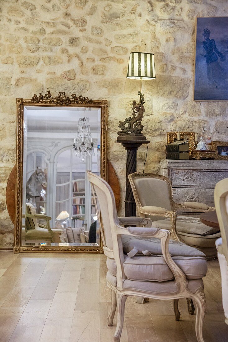 Gilt-framed mirror leaning against stone wall in elegant Belle Époque interior