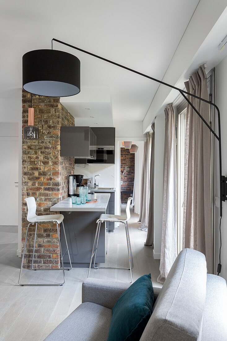 View from living room into open-plan kitchen with counter against vintage brick wall