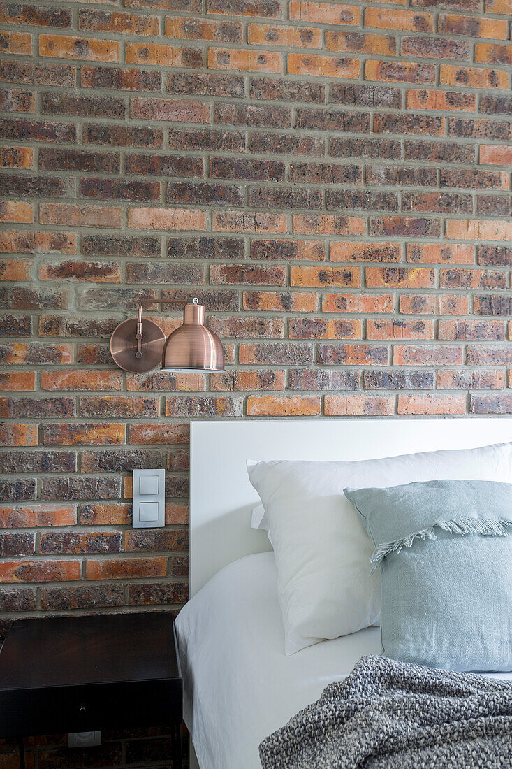 Double bed and sconce lamp on vintage brick wall in bedroom