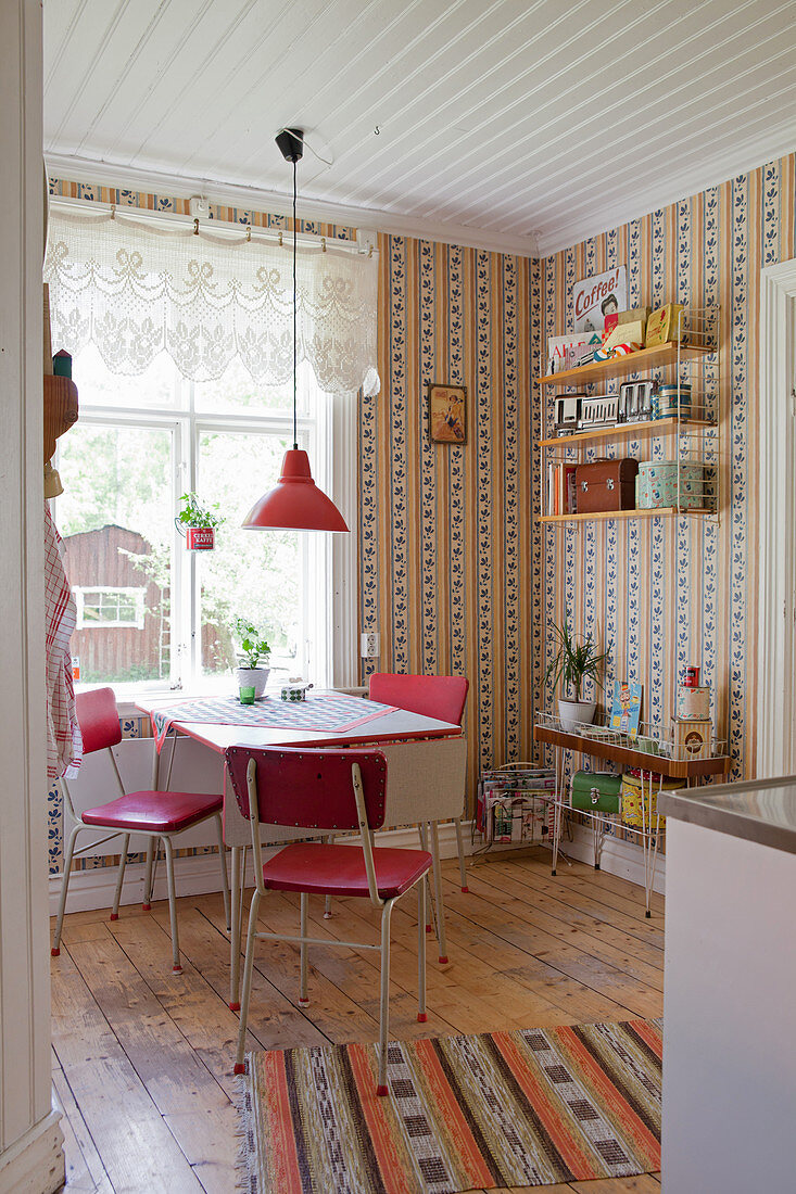 Red retro chairs around table in kitchen-dining room with vintage-style wallpaper