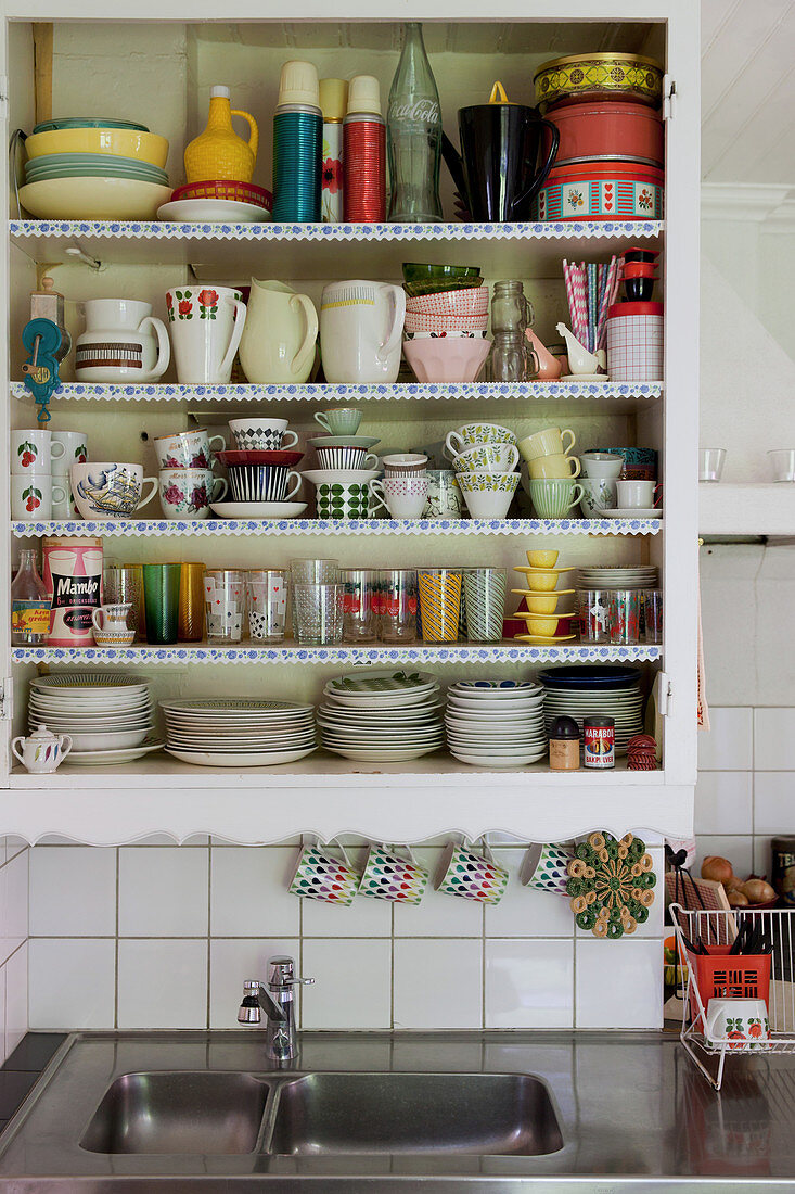 Retro-Geschirr im Küchenregal mit Spitzenborten über der Spüle