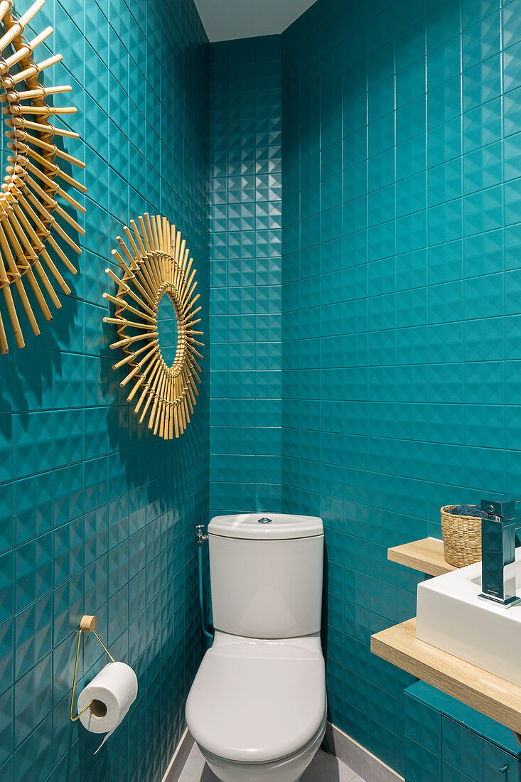 Toilette mit türkisblauen Wandfliesen und Sonnenspiegeln
