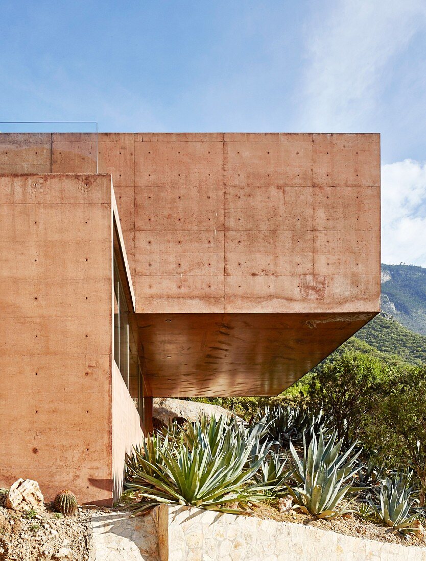 Modernes Architektenhaus aus rot gefärbtem Beton in den Bergen