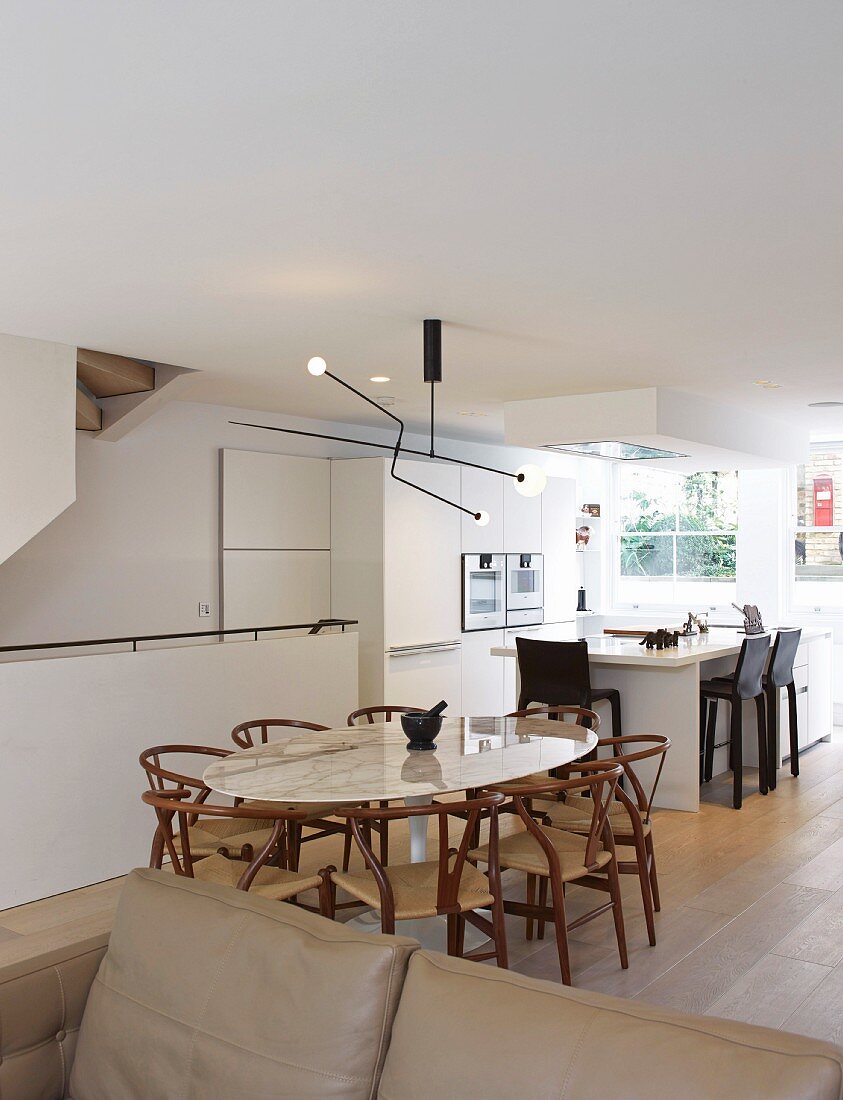 Offener Wohnraum mit ovalem Esstisch vor der modernen Küche