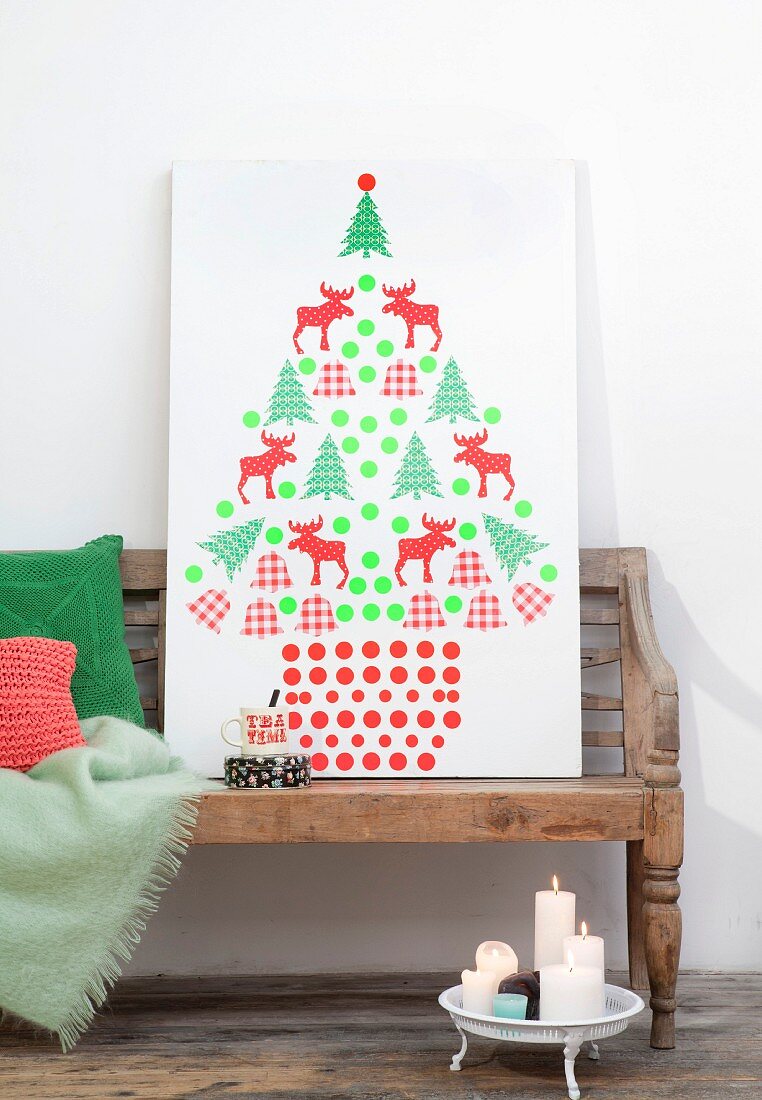 Stilisierter Weihnachtsbaum aus ausgeschnittenen Motiven auf weiße Platte geklebt
