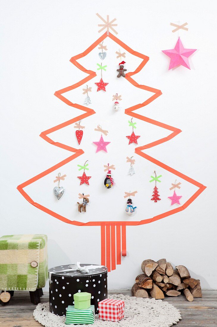 Weihnachtsbaum aus Masking-Tape auf weißer Wand und mit verschiedenen Anhängern