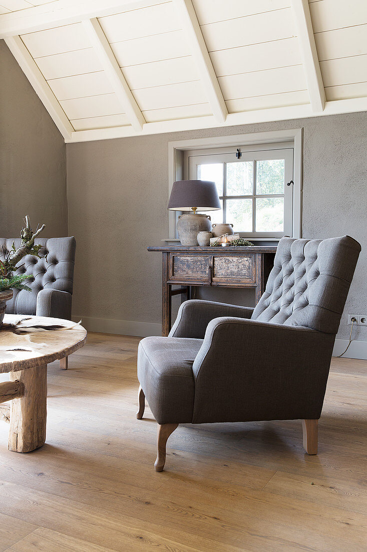 Klassischer Sessel im Wohnzimmer mit grauer Wand und Holzboden