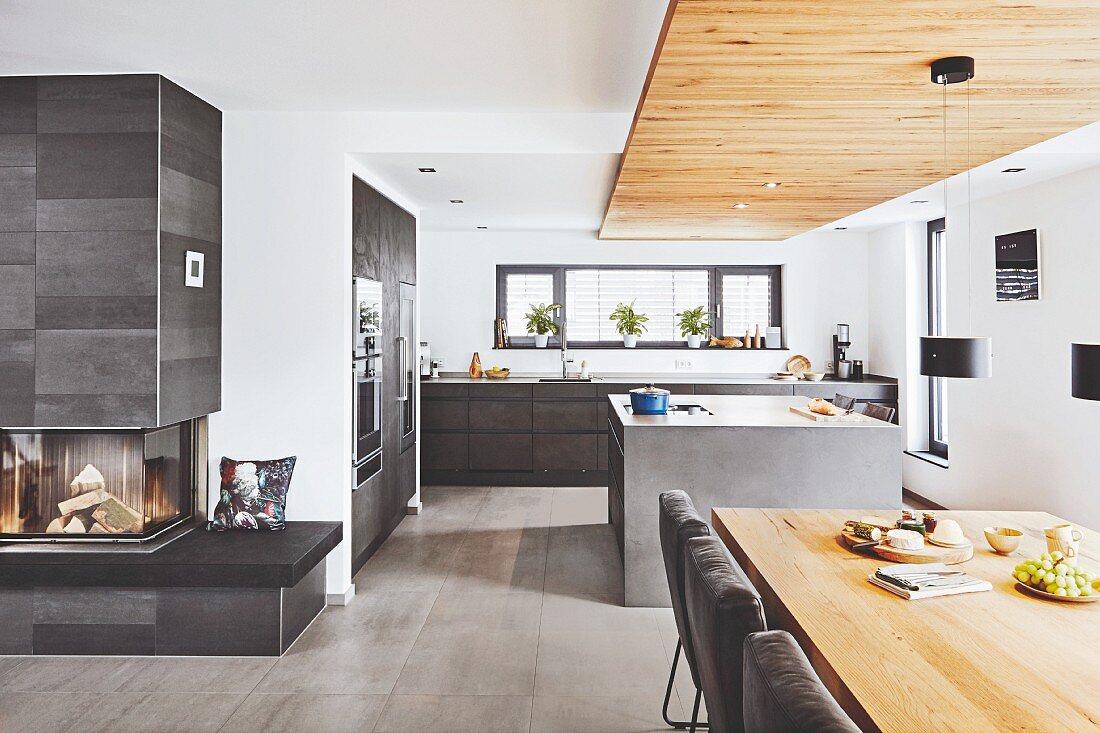 A minimal, open-plan kitchen with suspended reclaimed wood ceiling