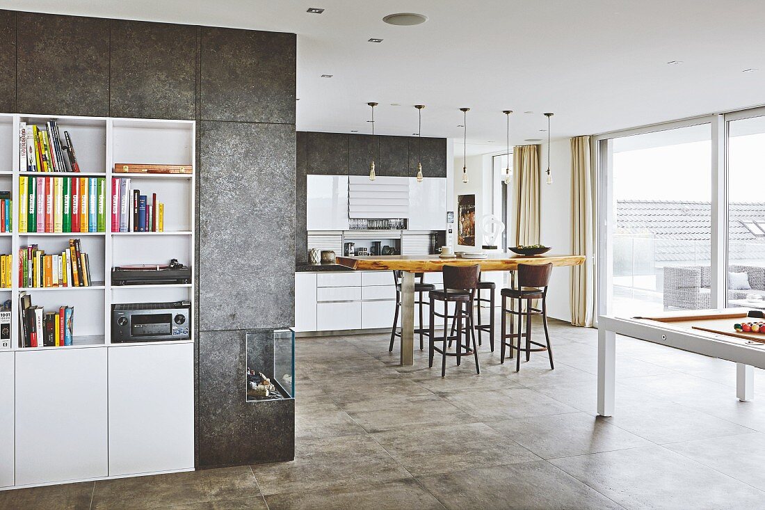 Weisses Einbauregal umgeben von beschichteter Wand und Gaskamin, Blick in offene Küche