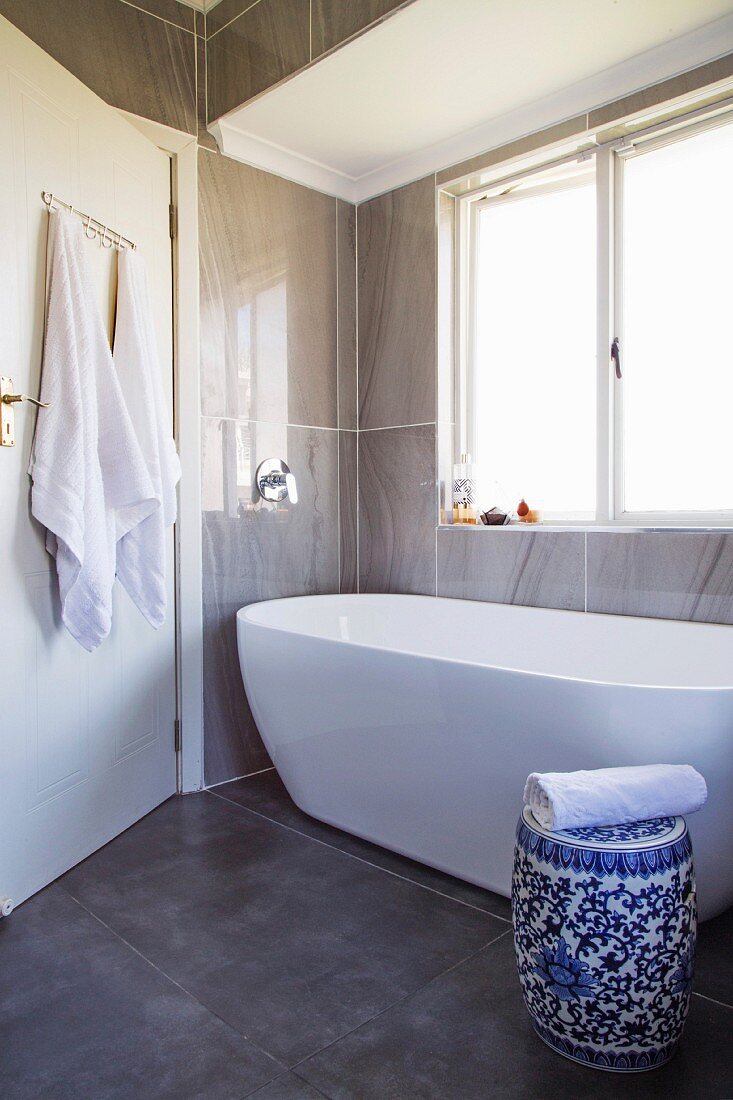 weiße Badewanne in modernisiertem Bad mit blau-weißem Porzellanhocker