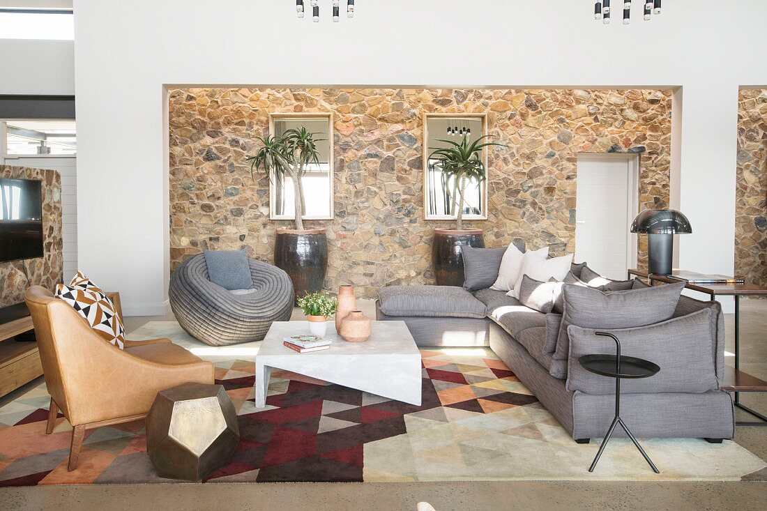 Elegante Lounge mit grauer Polstergarnitur und steinverkleideter Wand