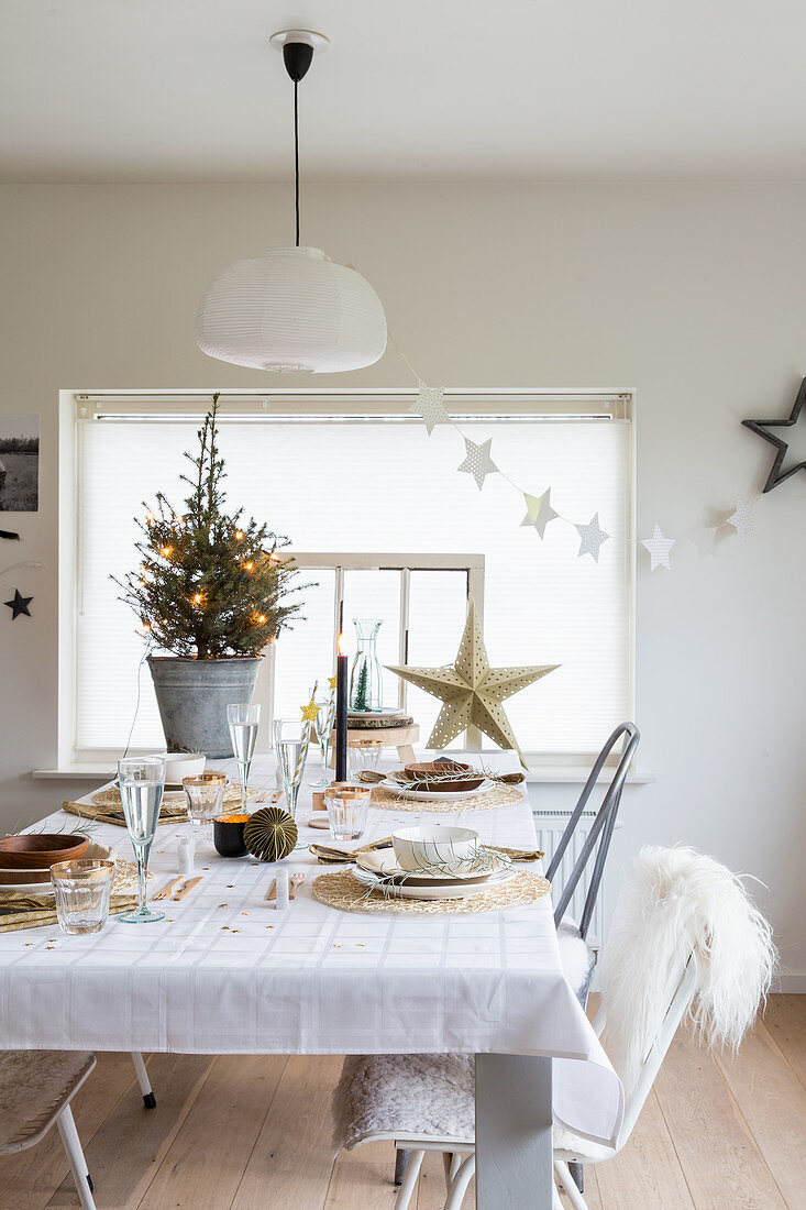 Festlich gedeckter Esstisch ganz in Weiß mit Weihnachtsbäumchen