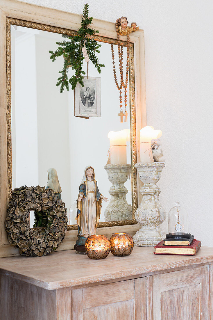 Madonnenfigur, Kerzendeko und ein großer Spiegel auf dem Schränkchen