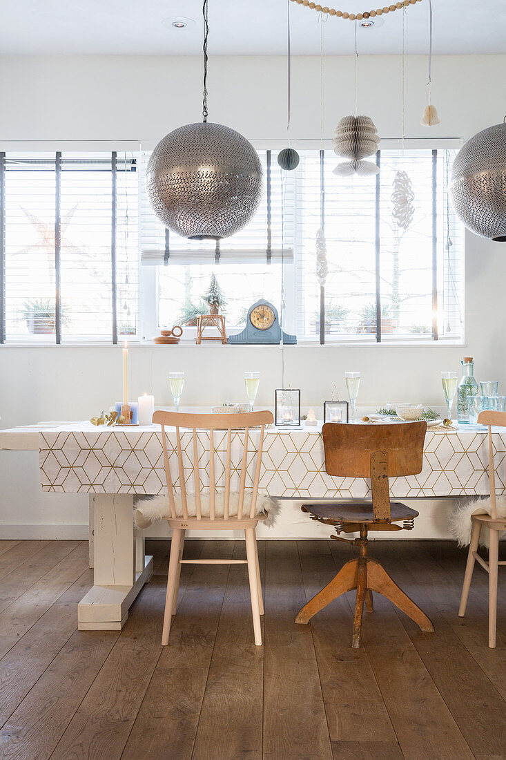 Spherical silver lamps above dining table and various chairs