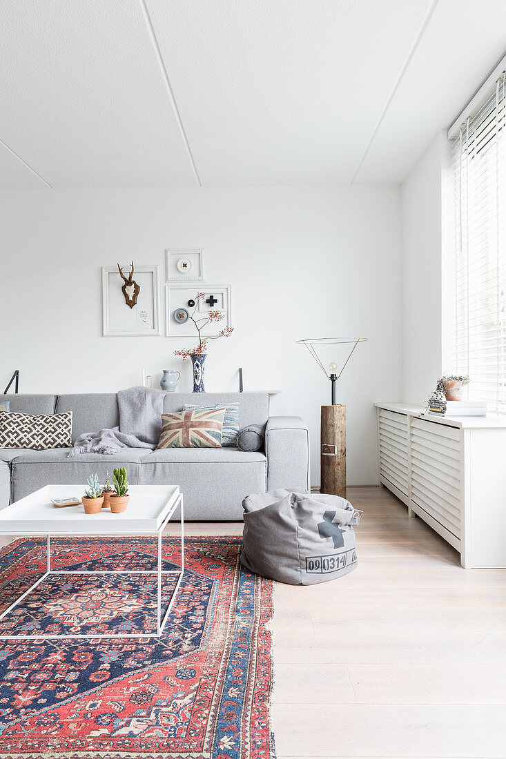 Old rug and modern grey sofa in white living room