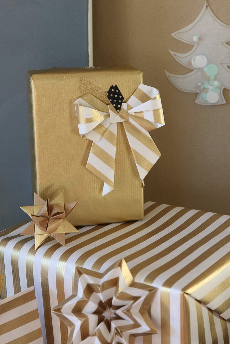 Weihnachtsgeschenke dekorativ verpackt in goldfarbenem Papier mit handgemachter Schleife